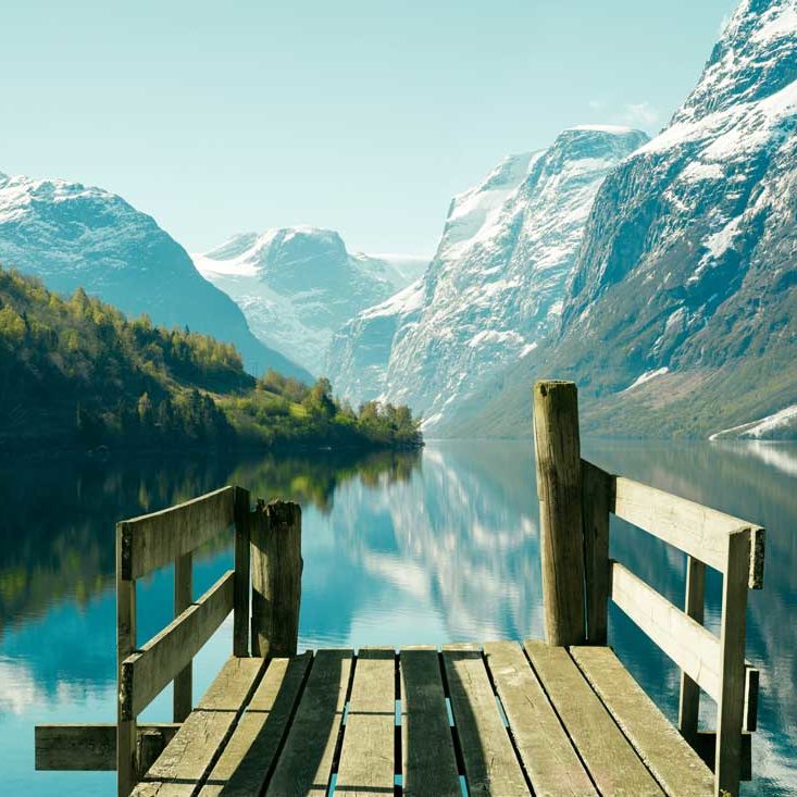 Flott utsikt fra brygge. Stupbratte fjell strekker seg opp fra Strynsvatnet. 