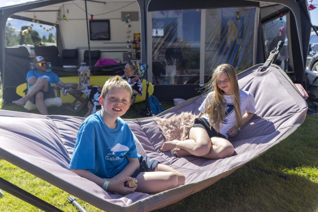 Barn som koser seg i hengekøye utenfor forteltet på campingvognen.