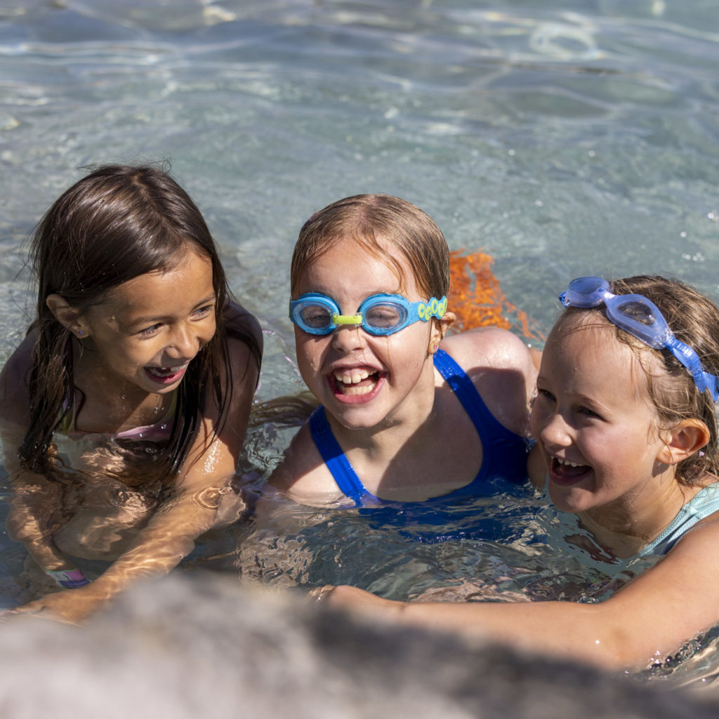 Tre barn koser seg i bassenget en varm sommerdag.